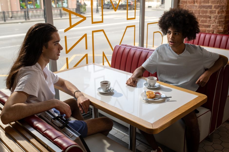 Two friends talking over coffee in a café window