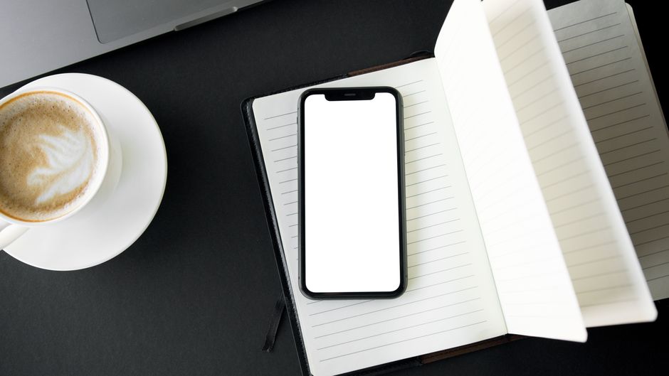 Two phones side by side on a desk, one showing a feed and one showing a photo gallery