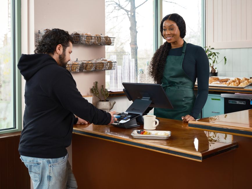 A customer paying at a café counter while staff serve them